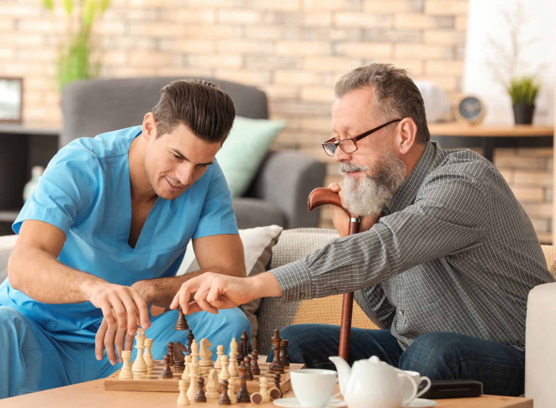 caregiver and old man playing chess